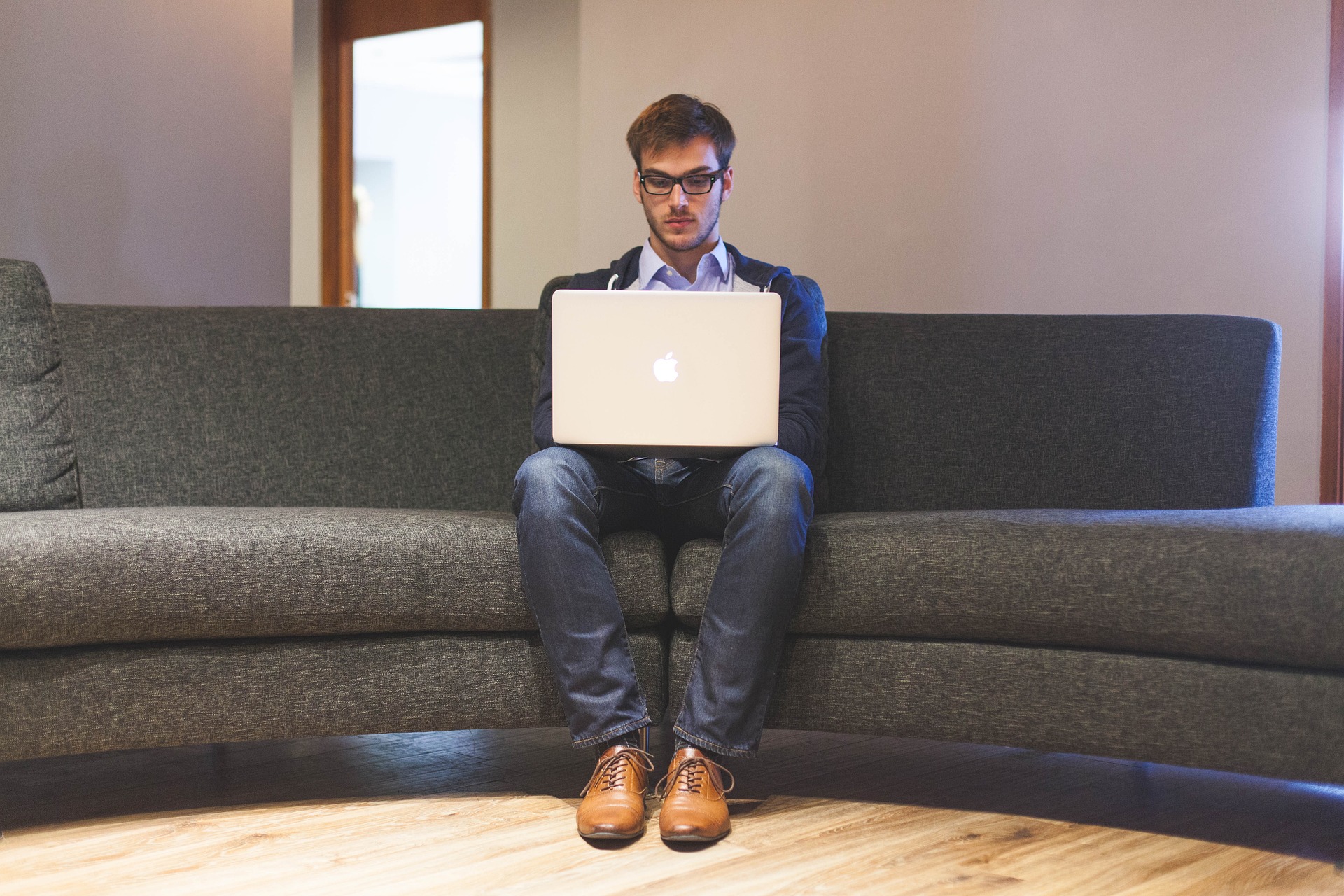 freelance installé sur un canapé avec un mac et chaussures marron